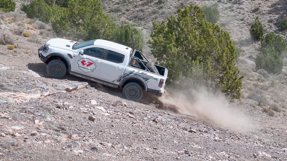 White Ford Ranger Raptor climbing a rocky slope at Five Mile Pass, with dust behind its rear wheels